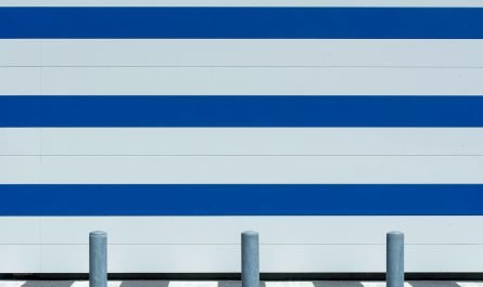 Mur minimaliste moderne avec des rayures bleues et blanches et des bornes dans un cadre urbain.