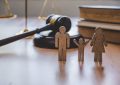 Figurines en bois représentant une famille devant un marteau de juge pour illustrer le Droit de la famille